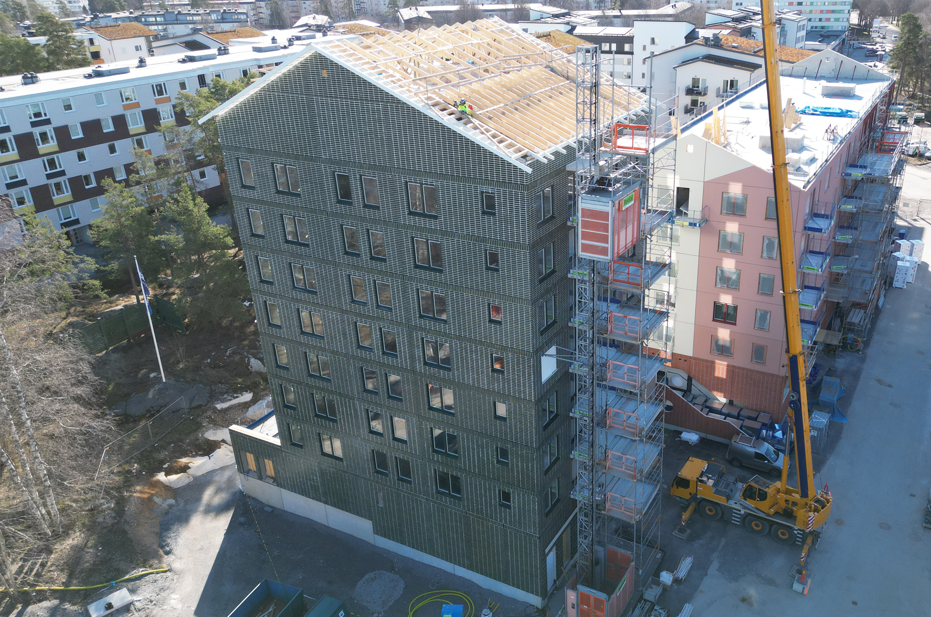 Lyftkran intill nybyggnationen av två flerbostadshus sett från luften.