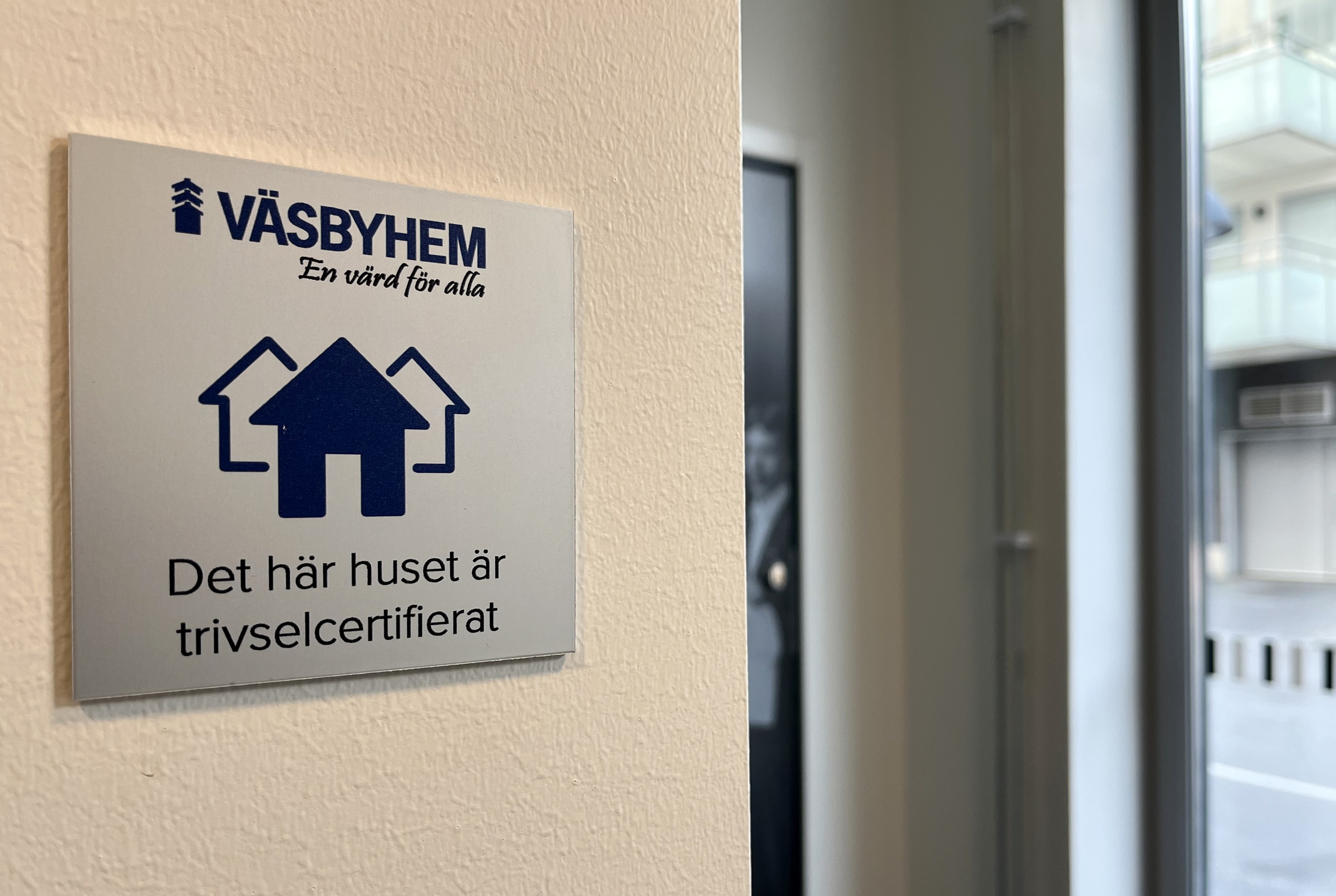 Plakett i silver och blått med Väsbyhems logotyp och texten det här huset är trivselcertifierat.
