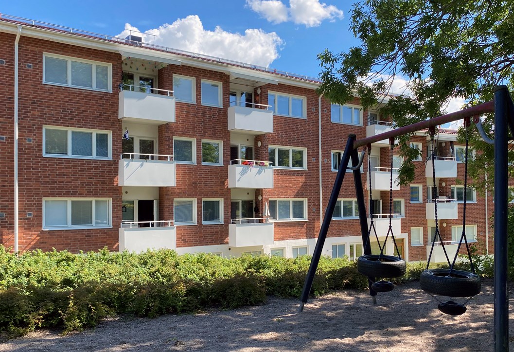 Flerbostadshus i tegel med en lekpark i förgrunden