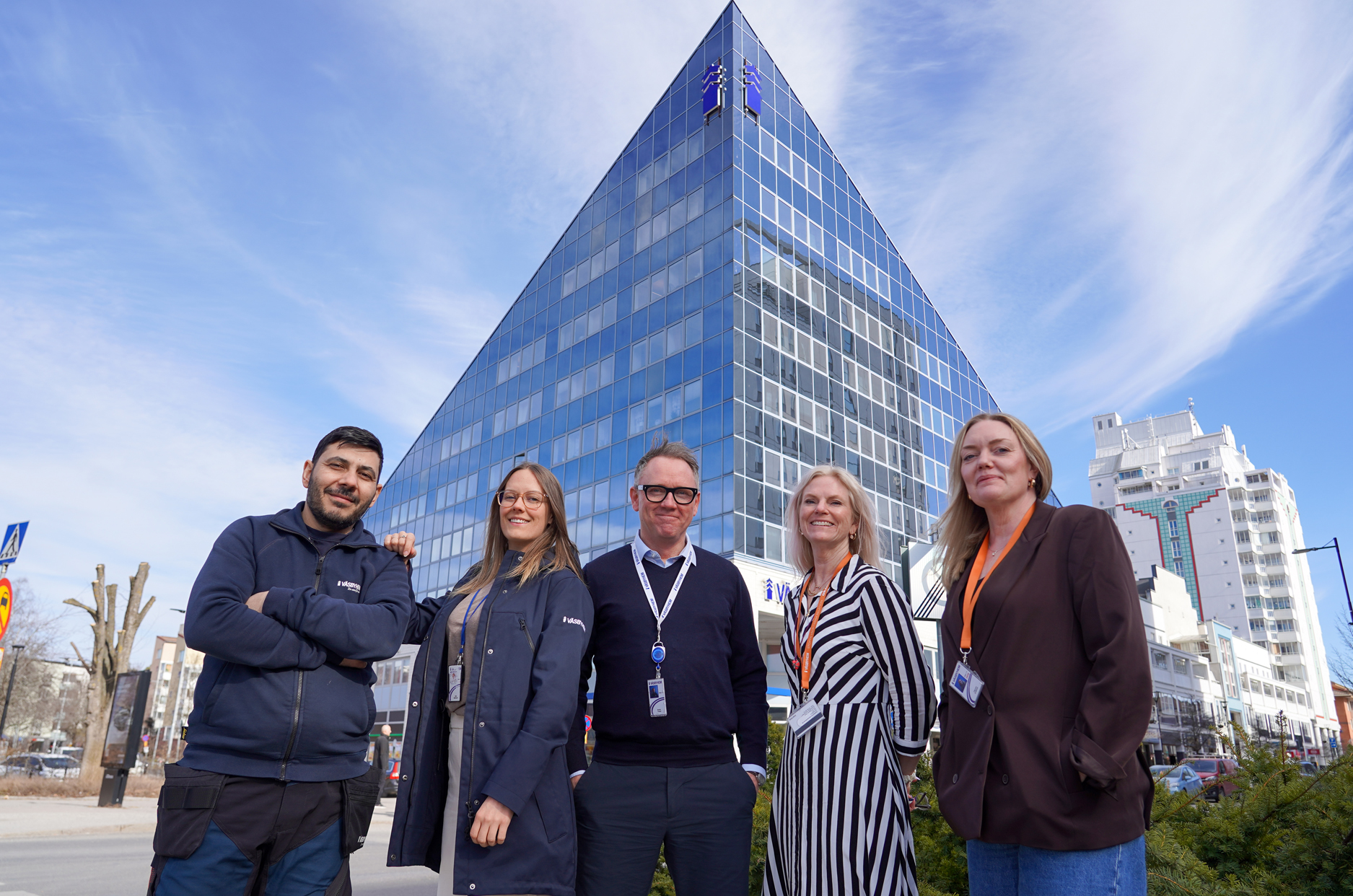 Tre kvinnor och två män står framför en blå pyramidliknande byggnad.