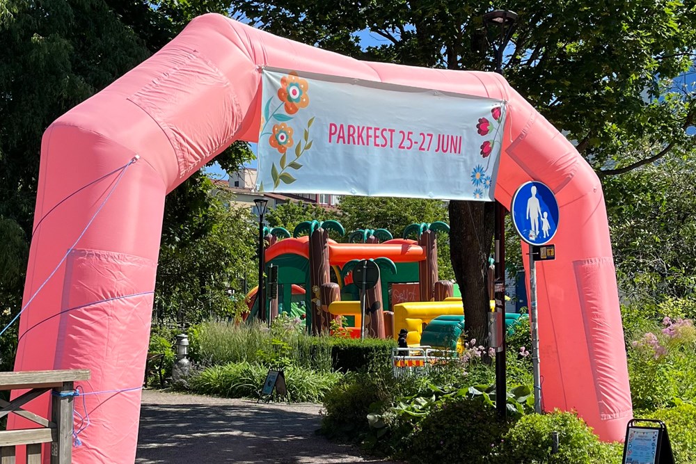 Uppblåst båge i rosa med vepa i överkant med texten Parkfest 25-27 juni.
