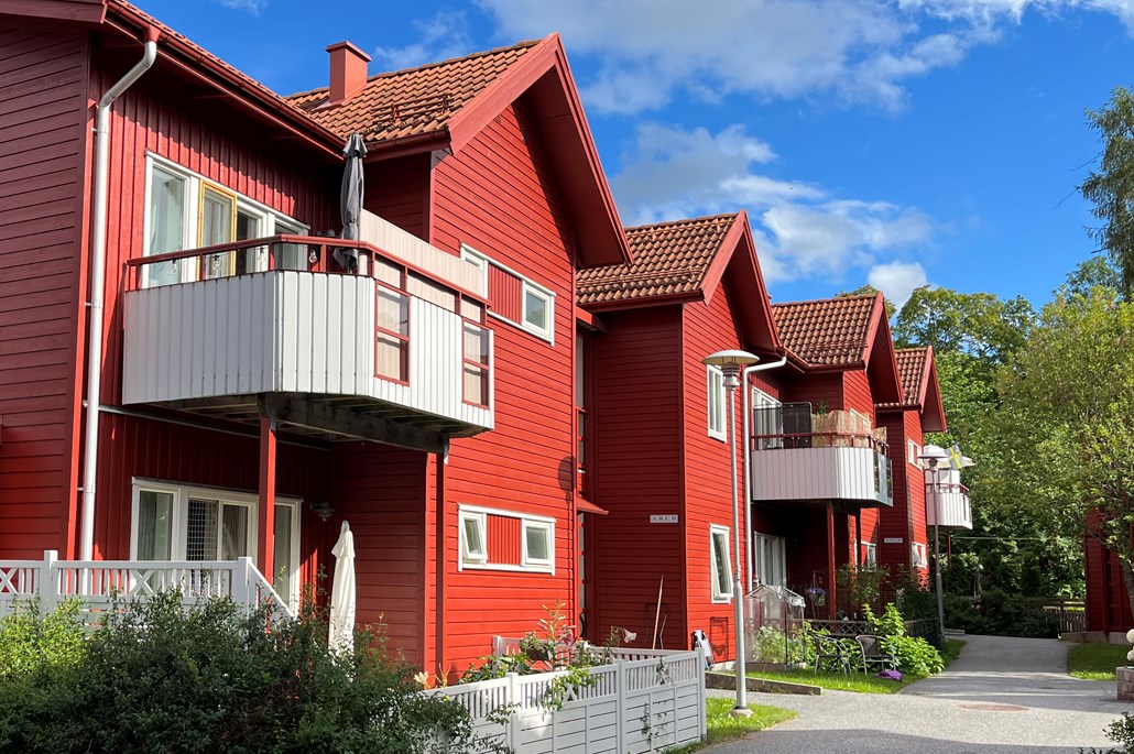 Röda tvåvånings flerbostadshus i trä med vita balkonger.