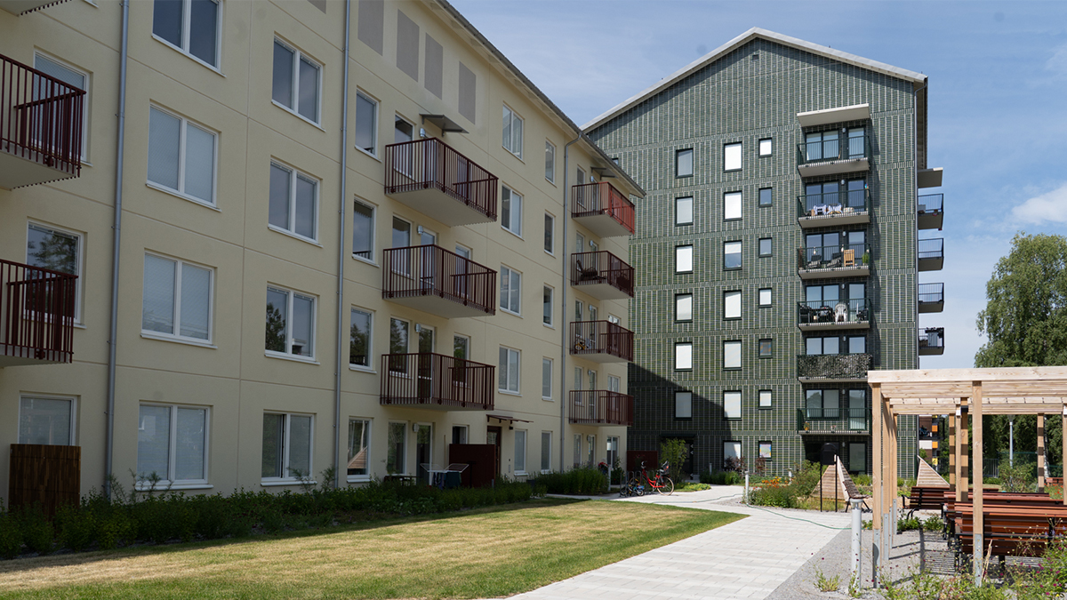 Exteriör bild på innergård med två flerbostadshus och en pergola.