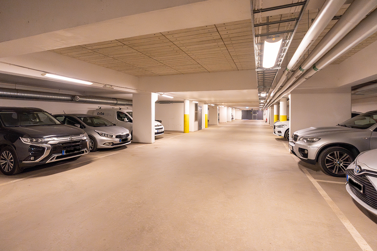 Interiör av parkeringsgarage med bilar parkerade på båda sidor.