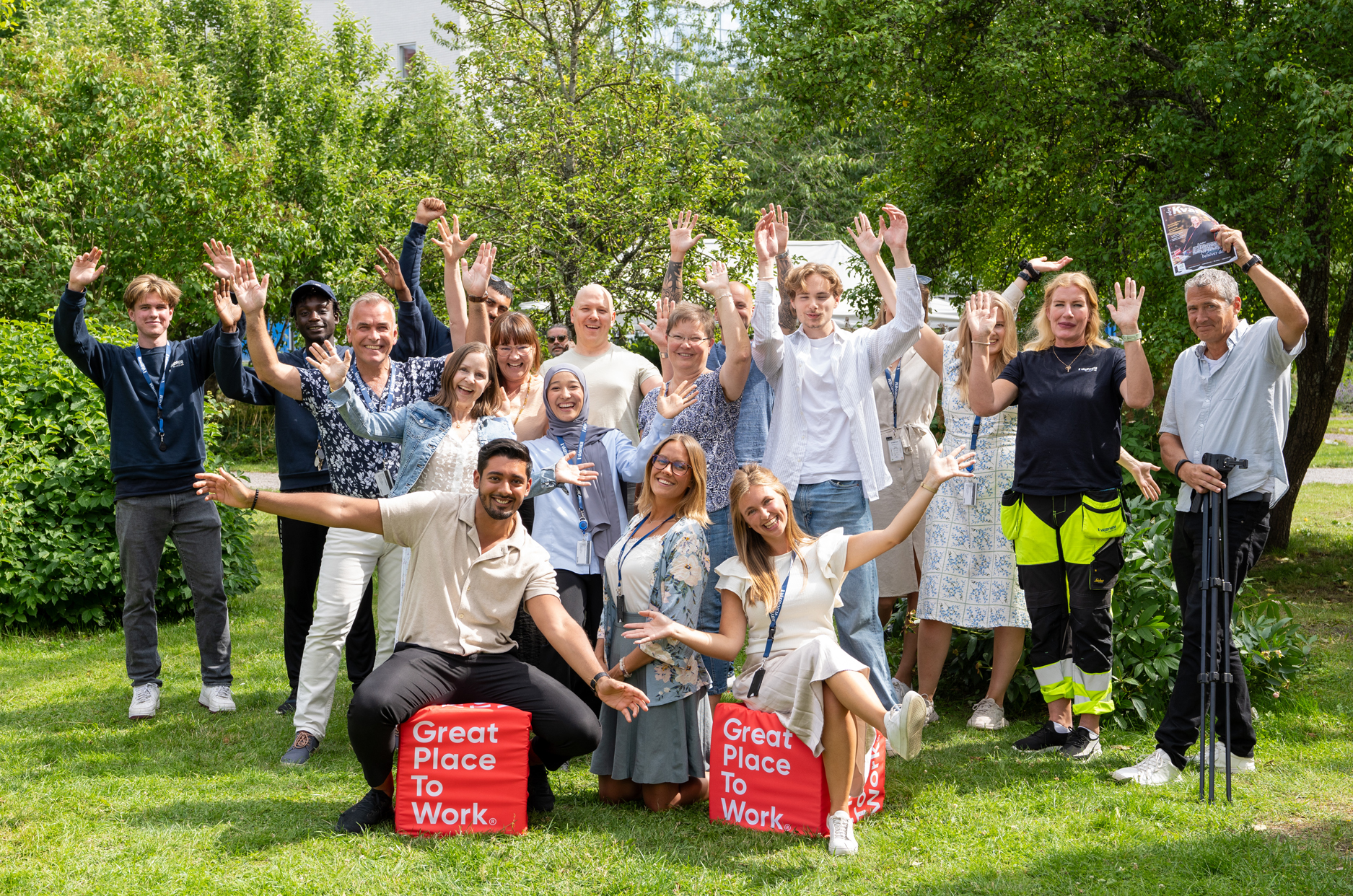 En grupp människor med armarna uppsträckta i en parkmiljö.