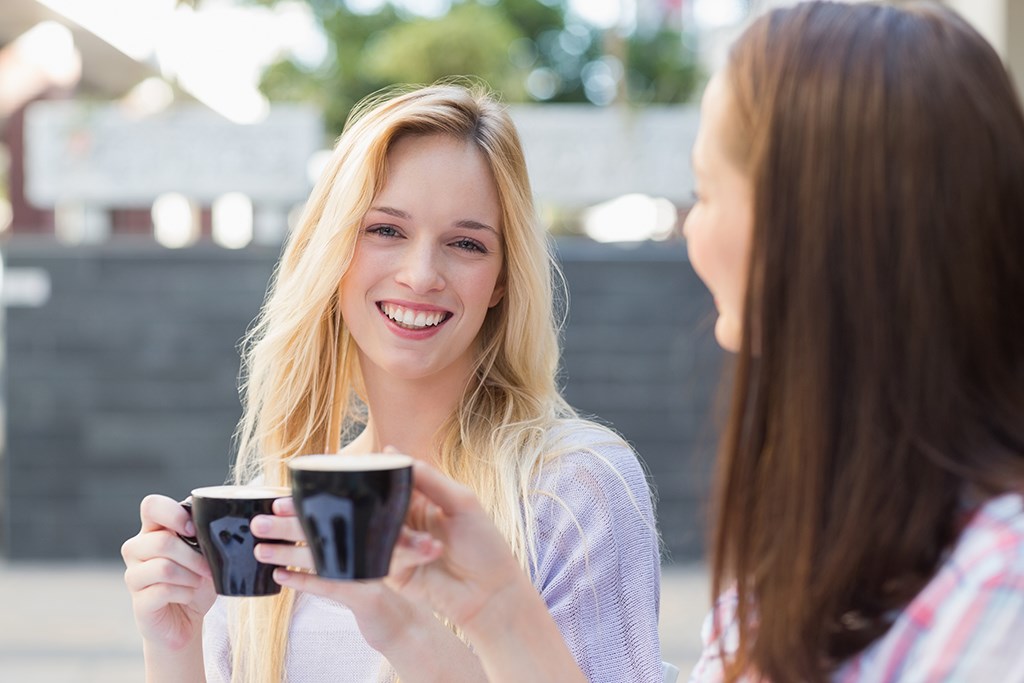 Två leende tjejer med kaffekoppar