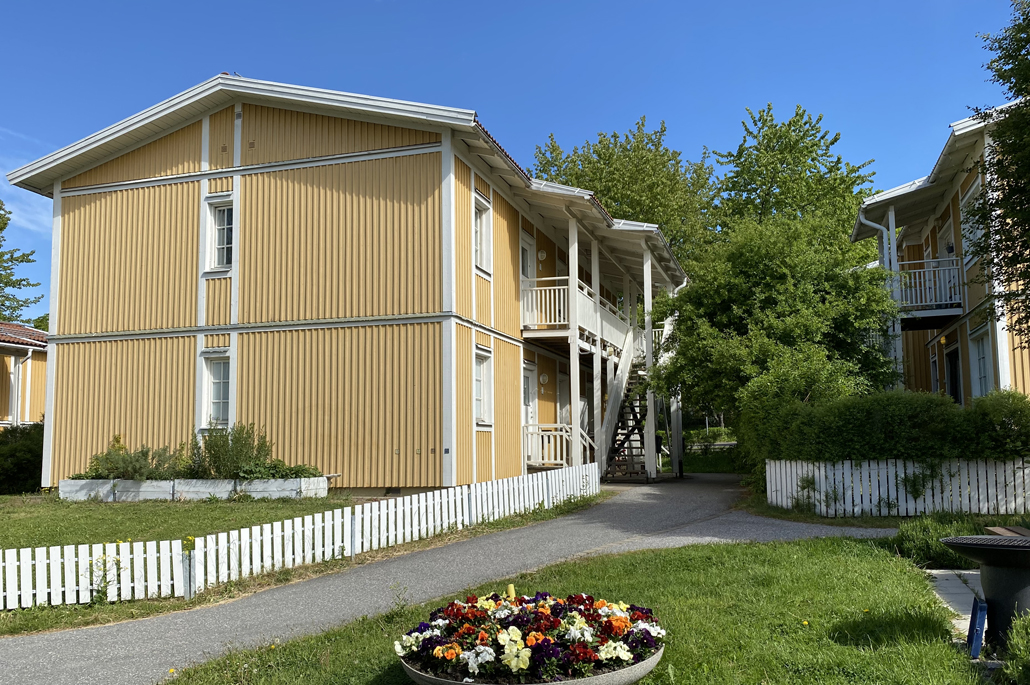 Tvåvånings gula och vita bostadshus i trä med loftgång.