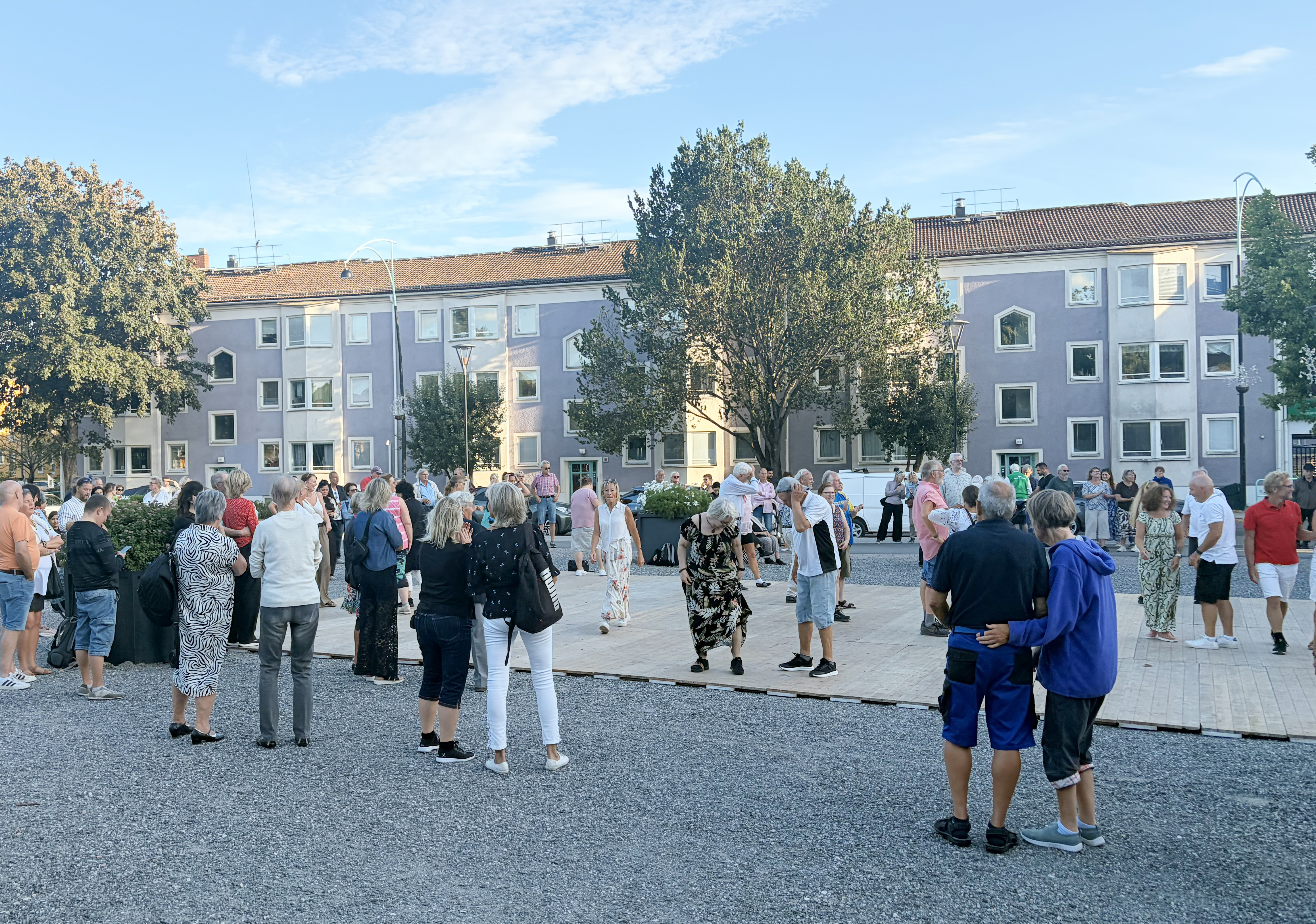 Människor som dansar utomhus framför ett hyreshus.
