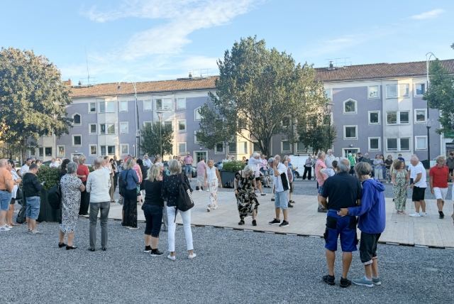 Människor som dansar utomhus framför ett hyreshus.