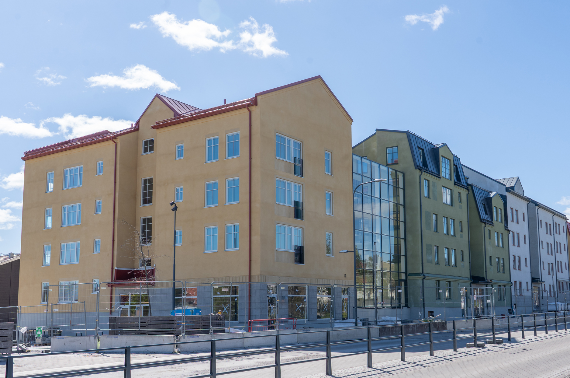 Flerbostadshus i gult, grönt och vitt invid en lokalgata.