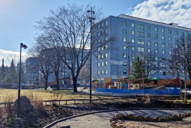 Blå byggnader på rad med park i förgrunden.