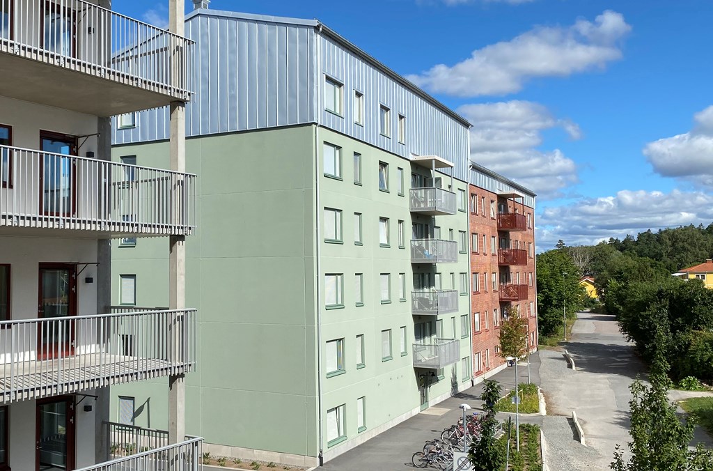 Loftgångar på ett flerbostadshus till vänster och ett flerbostadshus i grönt och rött i bakgrunden