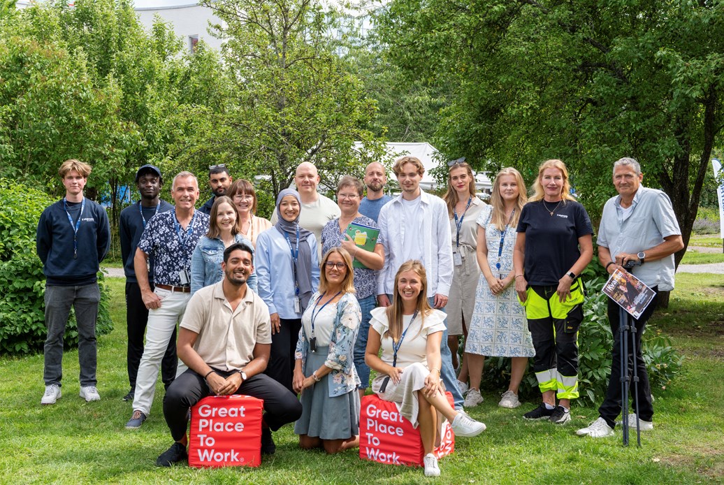 Människor i grupp uppställda i en grön parkmiljö.