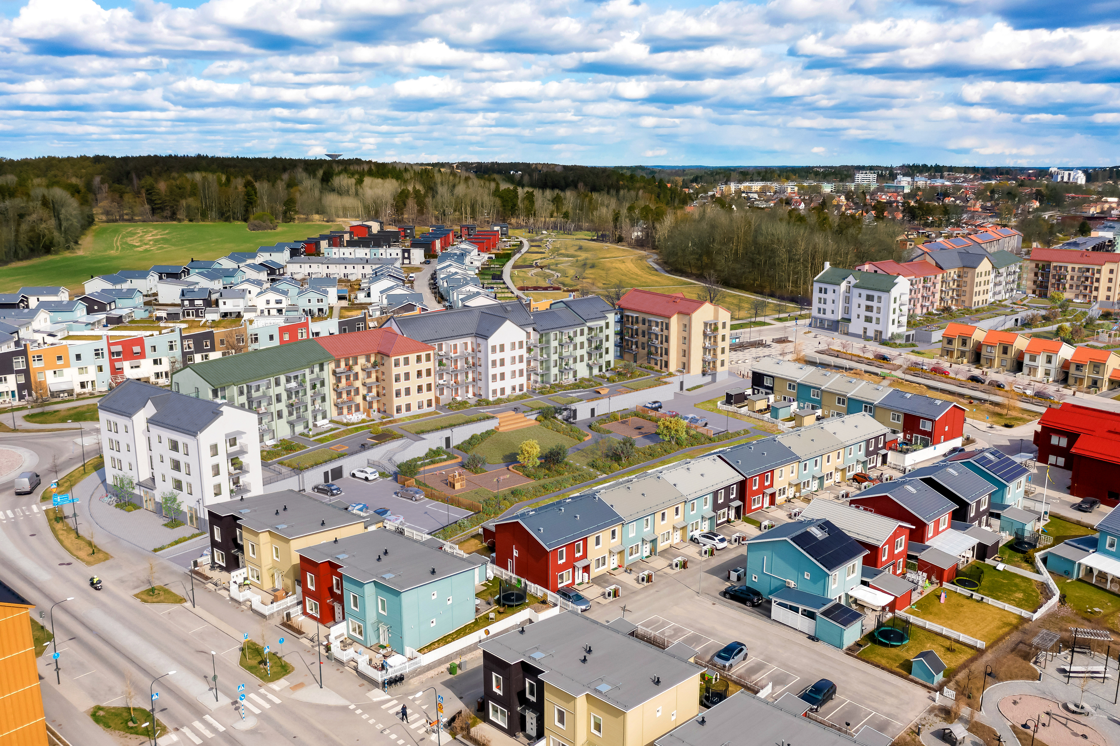 Bostadsområde med flerbostadshus och radhus i olika färger ur ett fågelperspektiv.