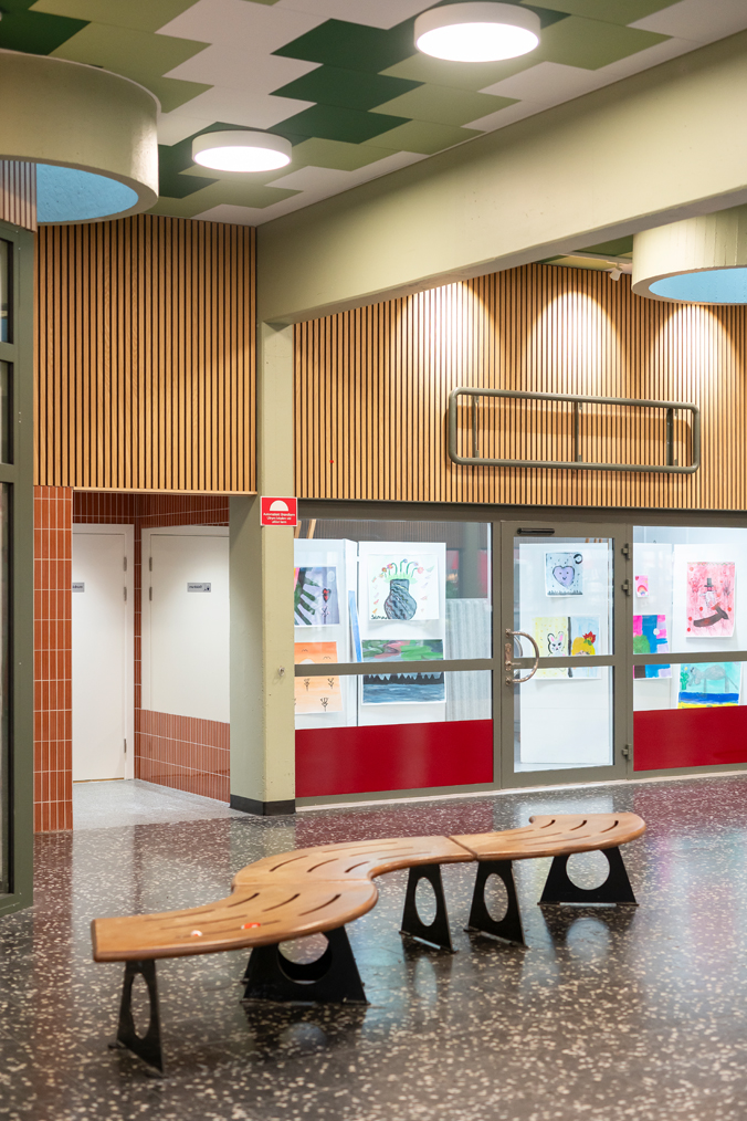 Interiör i inomhuscentrum med en svängd sittbänk i förgrunden.