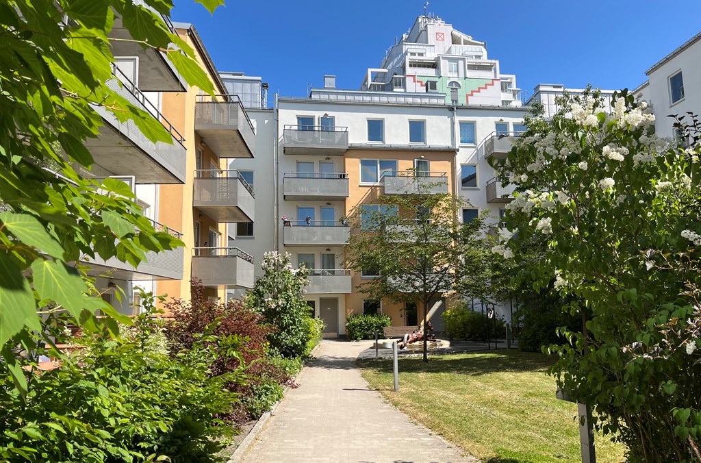 Femvåningars flerbostadshus i vitt och gult kring en innergård.
