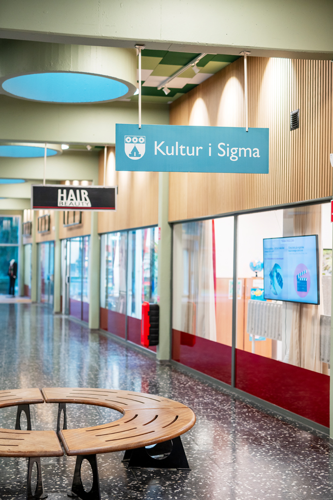 Interiör av ett inomhuscentrum med en rund bänk i förgrunden.