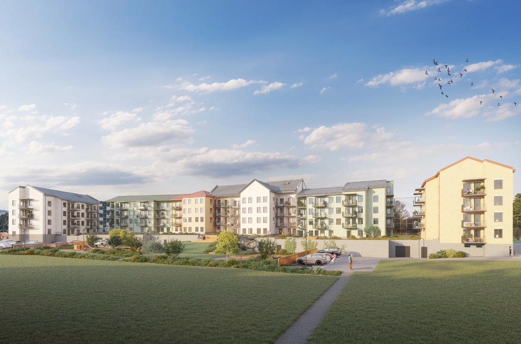 Gräsmatta och gångväg i förgrunden med en innergård och ett flerbostadshus i grönt, gult och vitt i vinkel